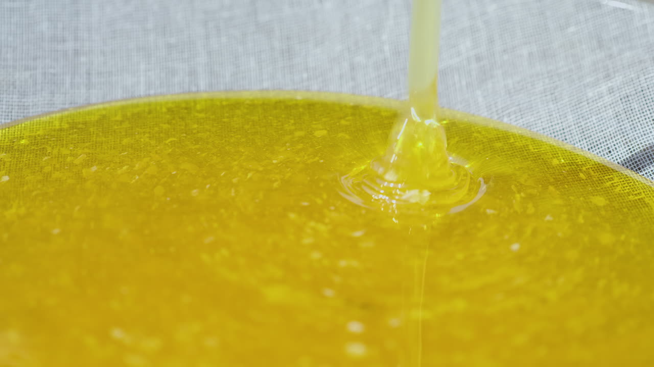 작은 가정 양봉장에서 꿀을 생산하는 신선한 여과되지 않은 꿀이 필터 4k 비디오로 흐릅니다.