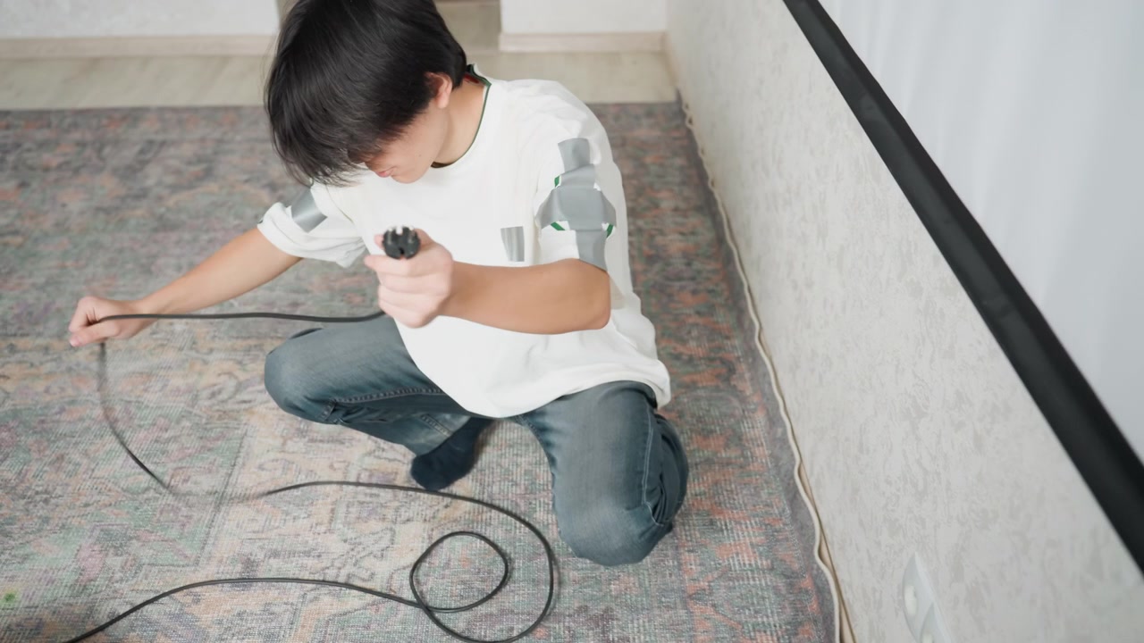 Individual neatly arranging cable loops. Someone carefully coiling extension cable on floor for storage purposes. Individual methodically organizing and coiling lengthy wire in cozy home environment