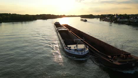 Antenne---Zwei-Lastkähne-Bei-Sonnenuntergang-In-Einem-Fluss-In-Den-Niederlanden,-Spinning-Shot