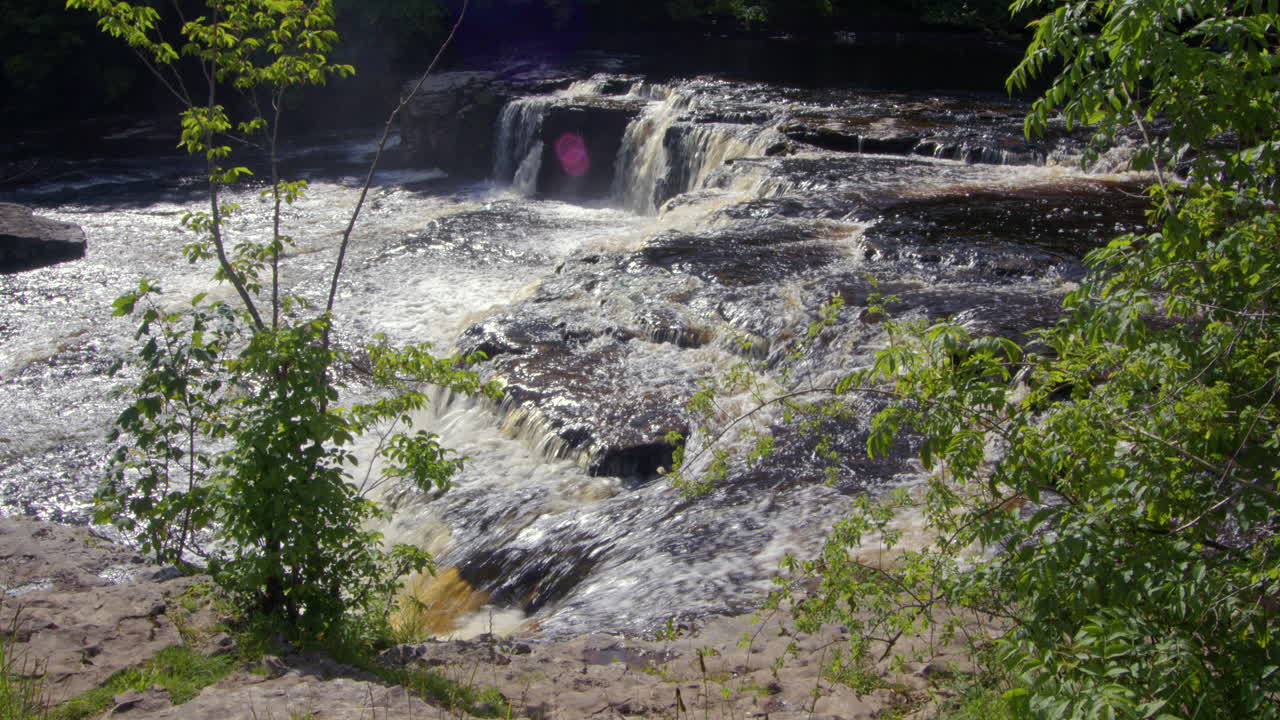 fotografía extra amplia de las cataratas superiores con follaje en primer plano en aysgarth falls en el río ure, yorkshire dales