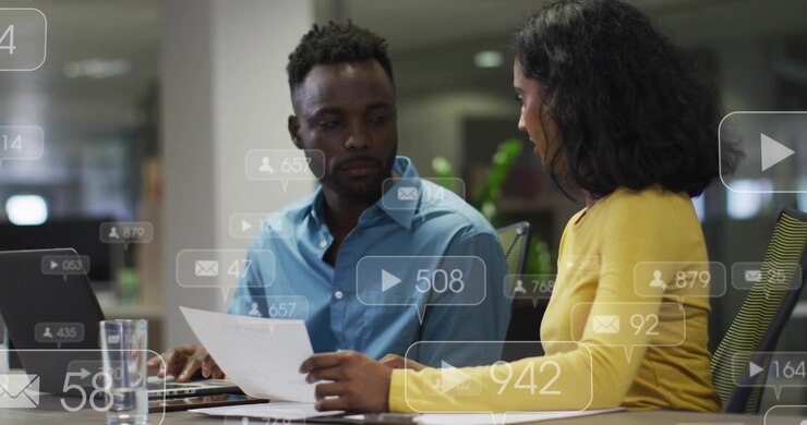 Duo chatting at desk pinging social icons bubbles counting boosting social reach laptop CTA showing