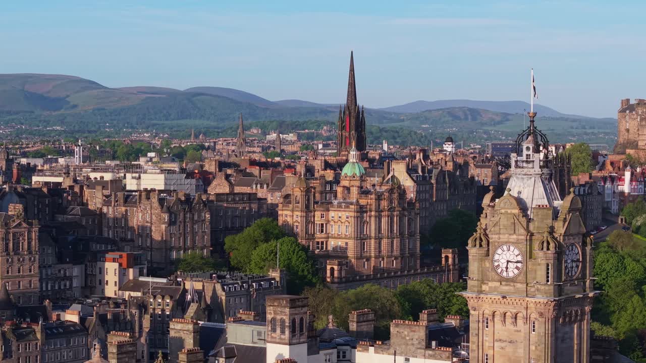 Um voo de drone paralelo suave capturando os edifícios tradicionais da Old Town de Edimburgo e terminando com uma revelação impressionante da Torre do Relógio do Balmoral
