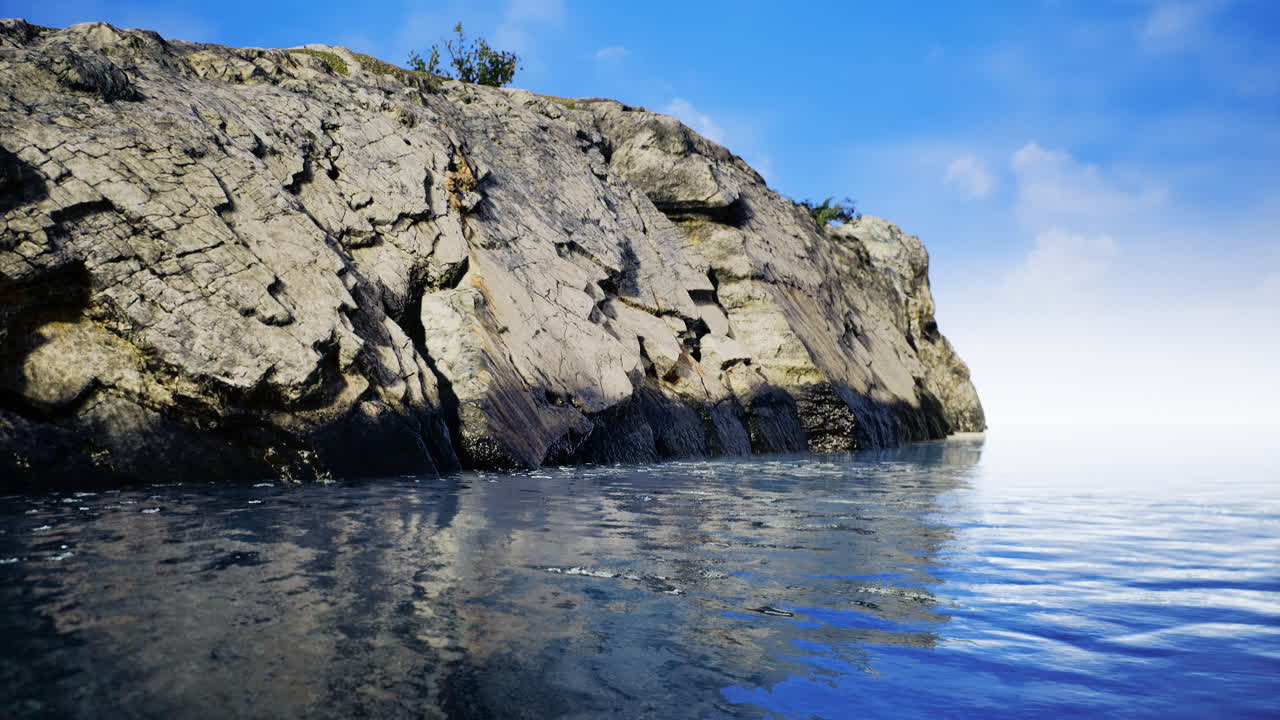Rocky coastline meets calm water under a clear blue sky at midday
