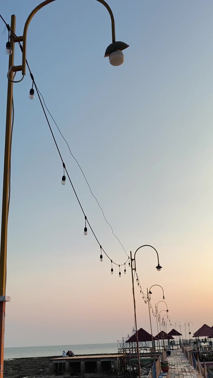 Luces de guirnalda colgando a lo largo de un muelle al atardecer