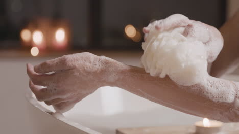 close up view of a woman taking a bath while rubbing her arms with soap