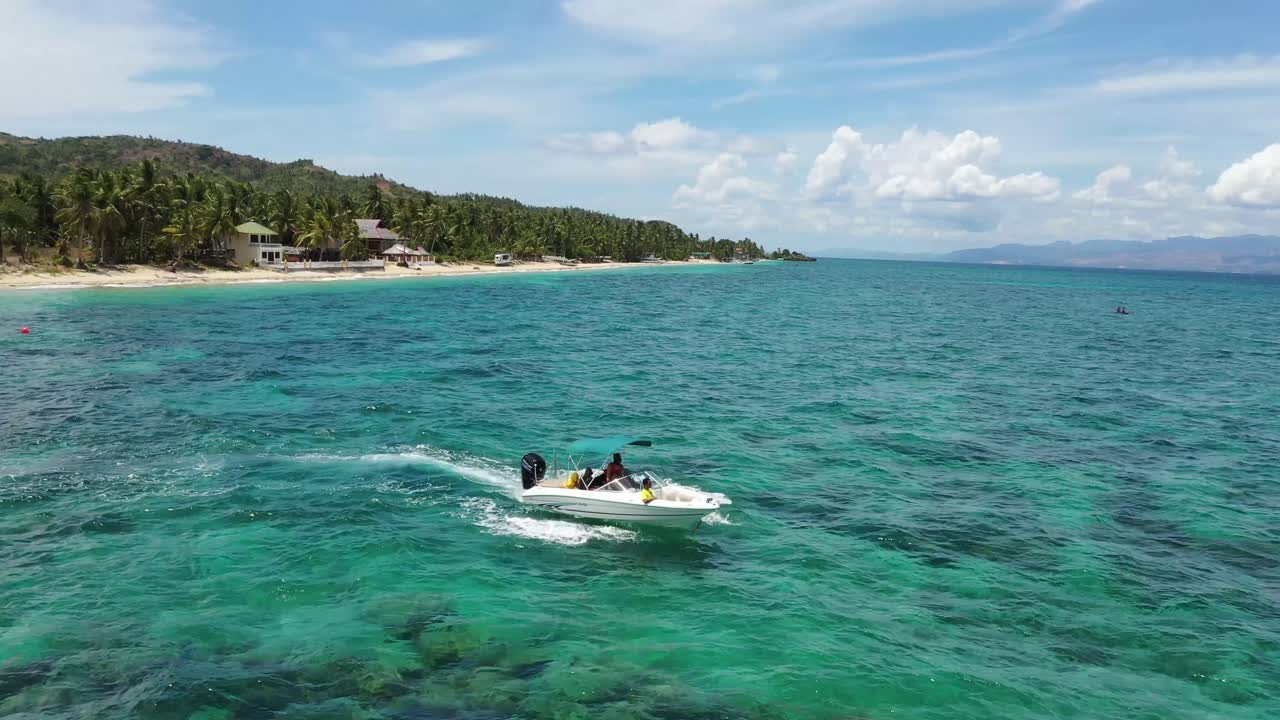 섬을 떠나는 맑은 청록색 바다 표면에서 파도를 통해 부서지는 흰색 스피드 보트