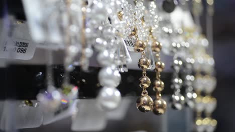 beautiful pearl necklaces with sparkling jewels in shop, closeup rack focus