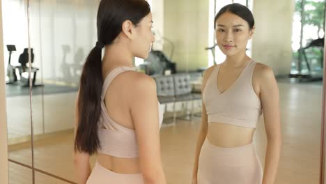 woman looking in mirror at gym