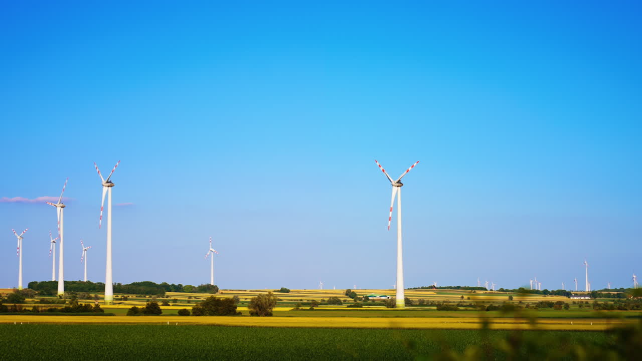 Turbines produce clean energy. Wind turbines stand tall against the clear blue sky, producing renewable energy in a serene countryside setting
