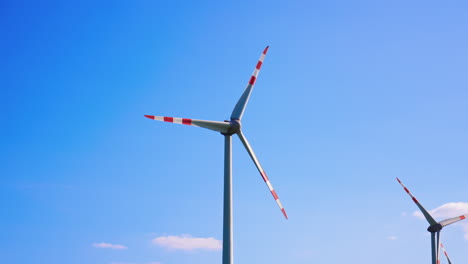 wind turbines produce clean energy. tall wind turbines with red and white blades spin against a clear blue sky, showcasing renewable energy in action