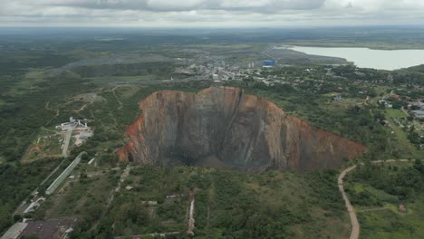 rising aerial peers down into big hole open pit of diamond mine in za