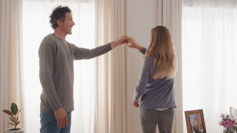 Feliz-Pareja-Joven-Bailando-Juntos-En-Casa-Celebrando-Divertirse-El-Fin-De-Semana-Sonriendo-Disfrutando-De-Un-Baile-Divertido-En-La-Sala-De-Estar-Celebración-De-Relaciones-Exitosas-Imágenes-De-4k