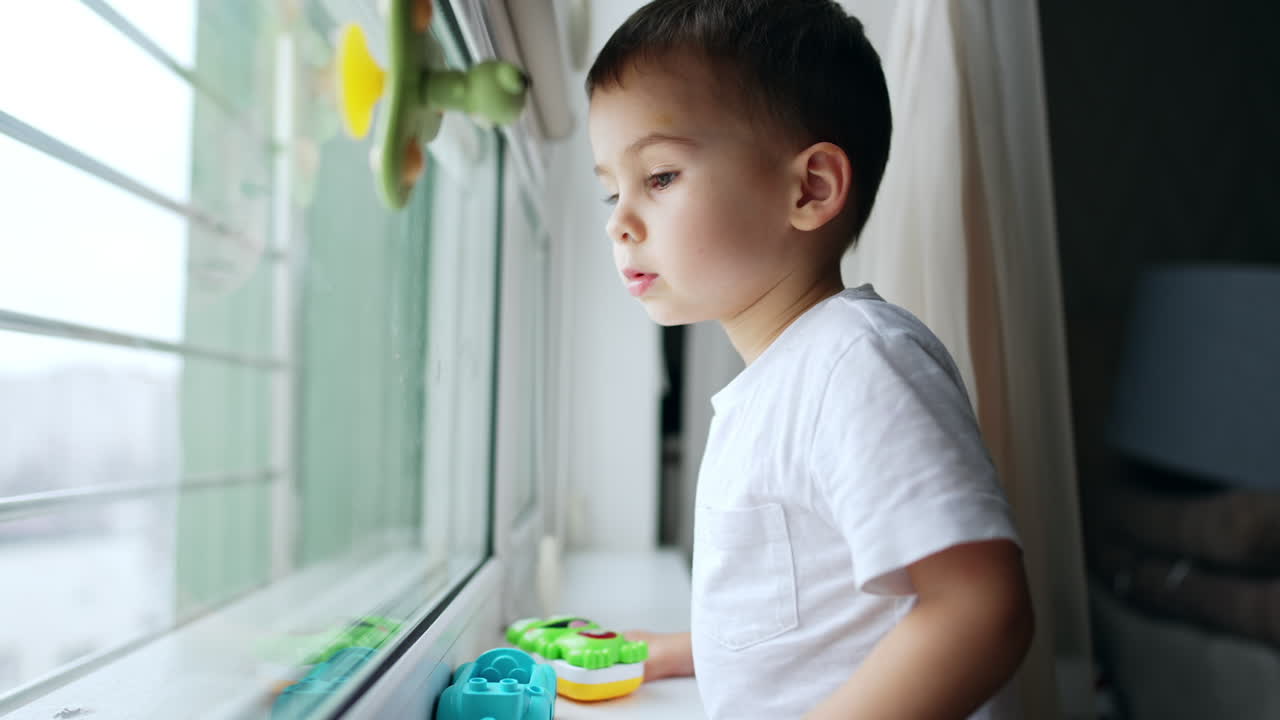 Child looking in window indoor. Sitting lifestyle happy boy.