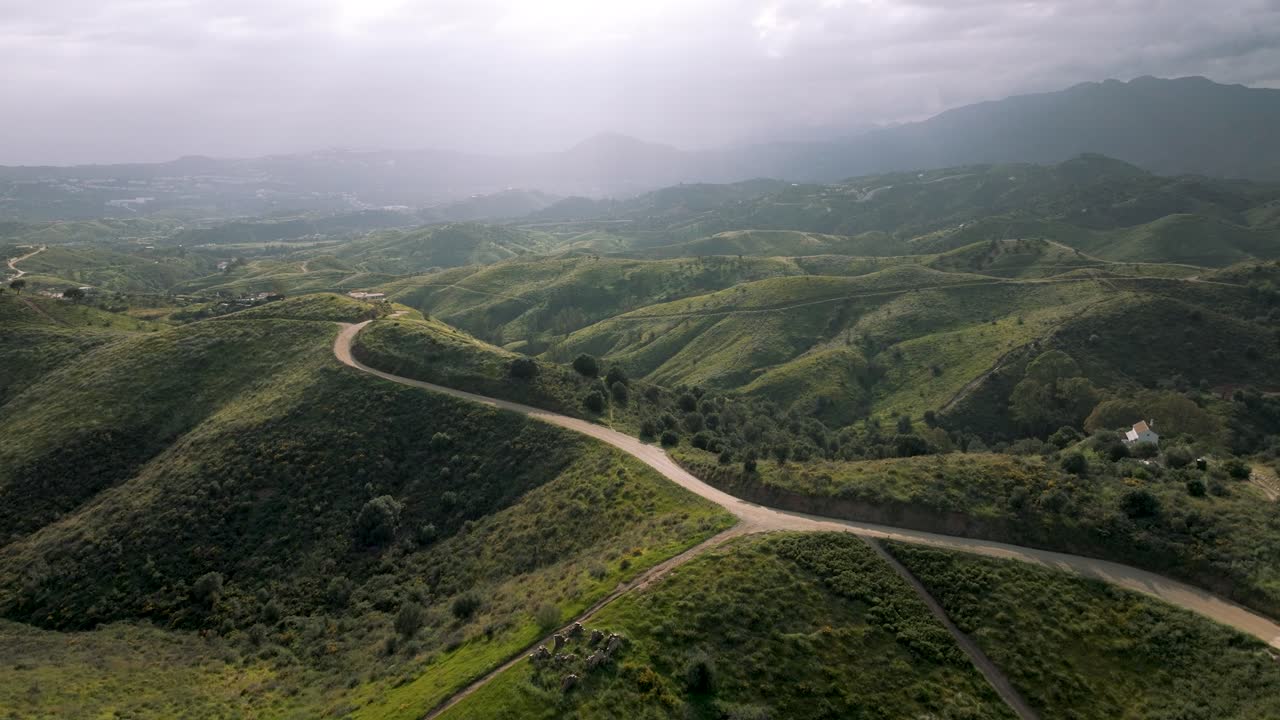 High-altitude drone image of a dirt path running through the mountainous terrain near Marbella, Spain, showing remote natural beauty.