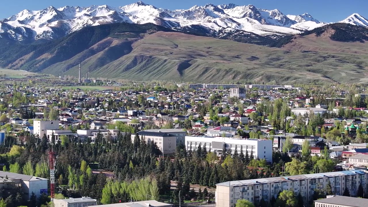 Edifici in stile sovietico e sfondo di alte montagne. Paesaggio urbano di Karakol ripreso da drone, Kirghizistan