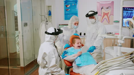 dentist doctor in coverall finishing dental treatment of child in stomatological clinic