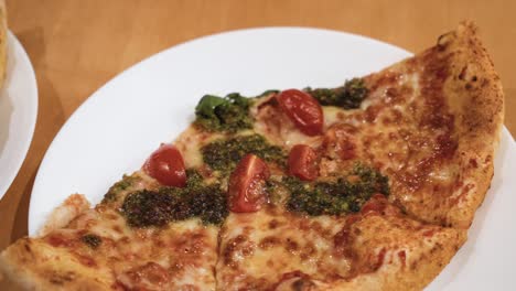 close-up-shot-of-delicious-Italian-pizza-slices-in-white-plates-on-the-wooden-table-at-home,-sliding