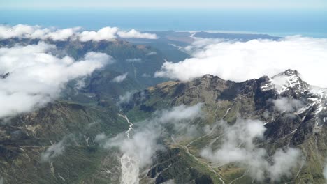 aerial shot from plane scenic flight over west coast fox glacier aoraki mount cook, national park with clouds, snowcapped rocky mountains and ocean in background