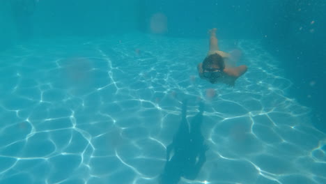 un niño nadando bajo el agua en una piscina