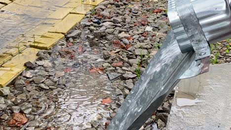 a large stream of water pours out of drainpipe during heavy rain. close-up. the season of heavy rains. water drops on puddles.