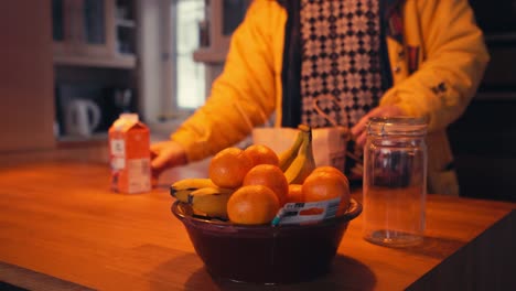 man is placing fresh orange fruits on a bowl on top of wooden table