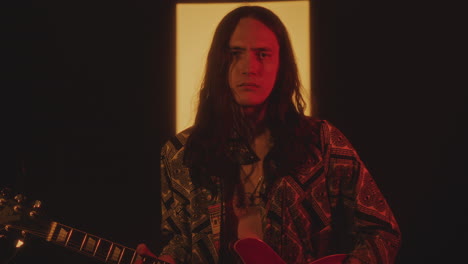 indie musician playing the guitar and posing on camera in studio