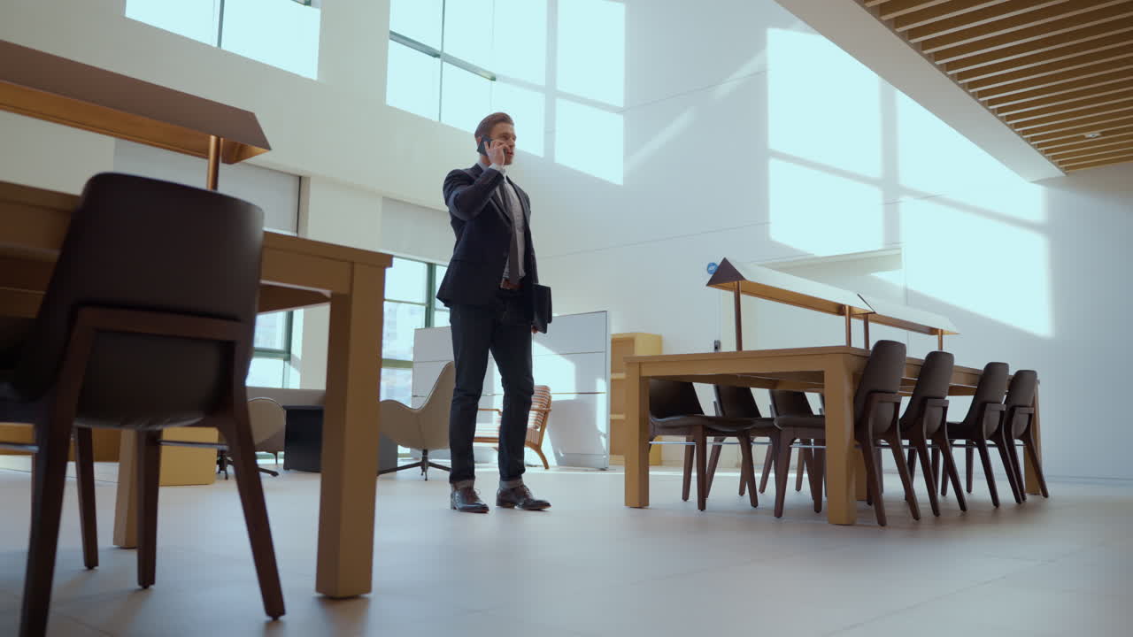 One Caucasian Businessman Talking on Phone In Spacy Modern Meeting Room With Panoramic Windows - push in low wide angle