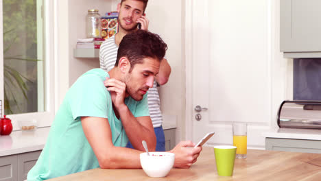 Friends-laughing-while-using-smartphones-in-the-kitchen