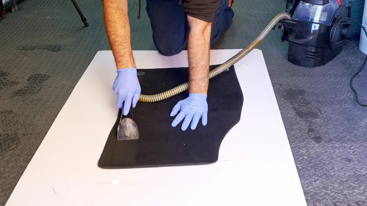 Extracting water from a large carpet car foot with a wet vac vacuum - medium shot