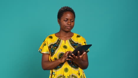 Smiling-happy-person-checking-internet-websites-on-her-tablet-in-studio