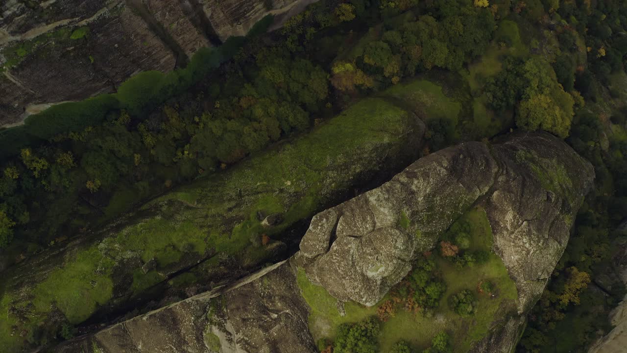 vista aérea sobre pilares empinados de arenisca y edificios en lo alto de un acantilado en meteora, grecia - de arriba hacia abajo, disparo de drones