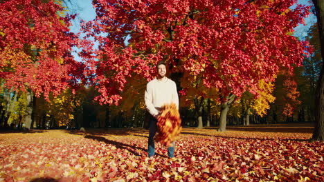 man playing with autumn leaves in a vibrant park