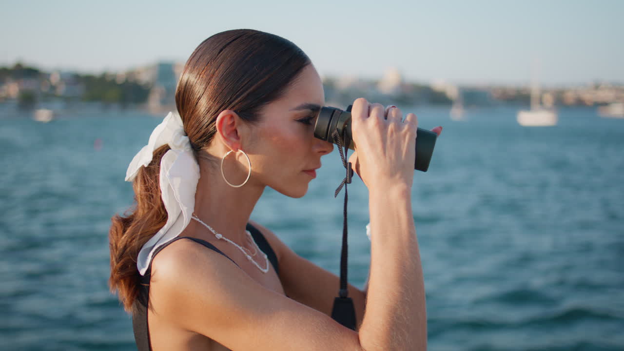 mujer usando binoculares junto al mar