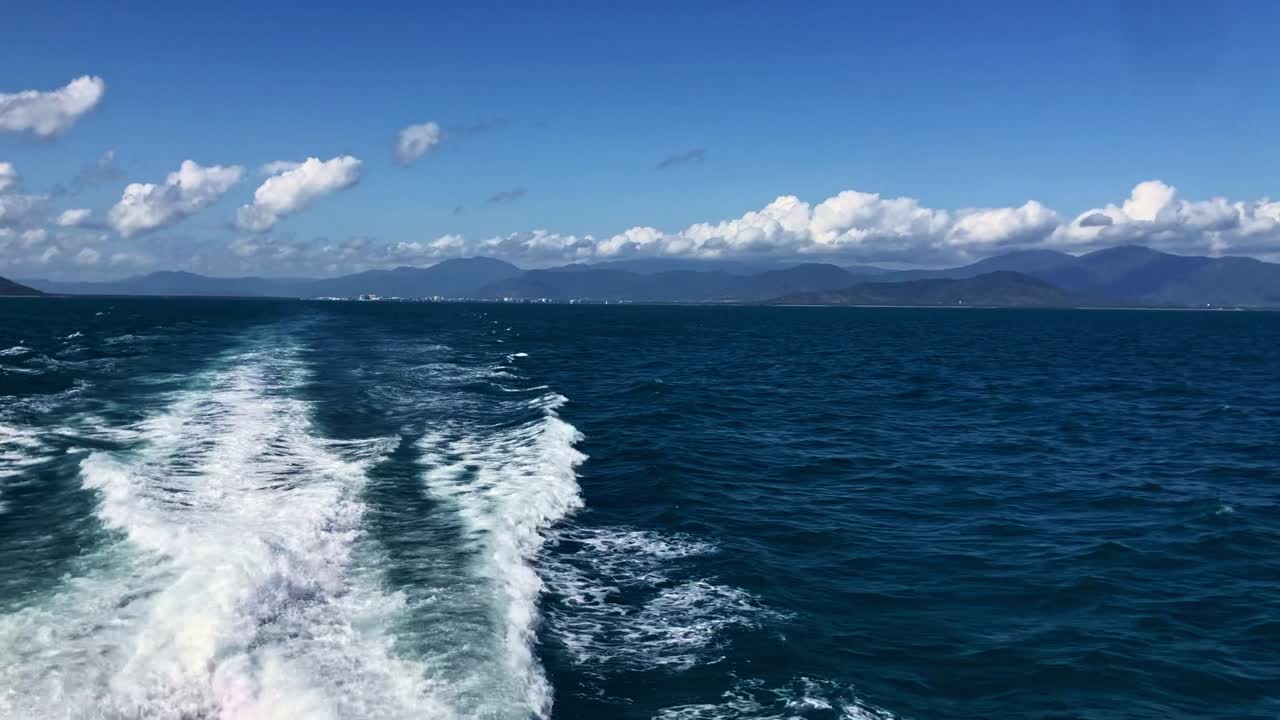 View of white water from stern of vessel open ocean islands in the distance