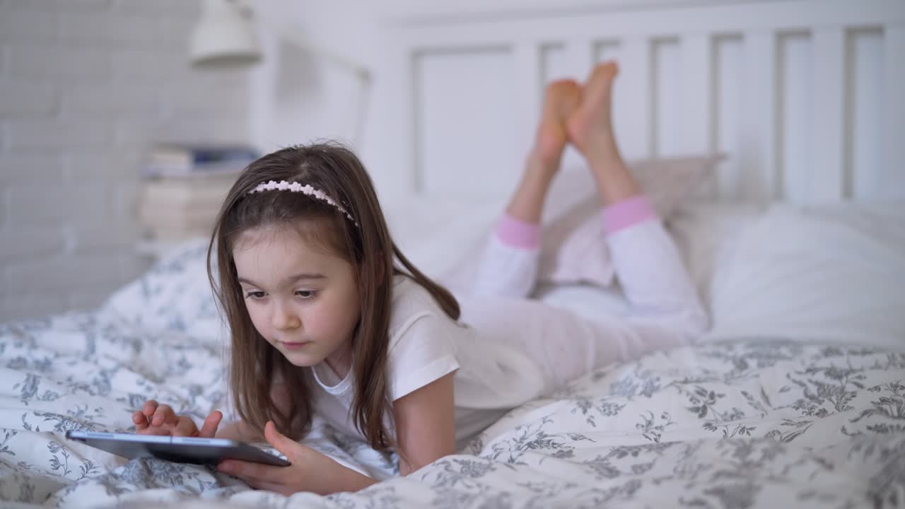 маленькая девочка с планшетом в постели.