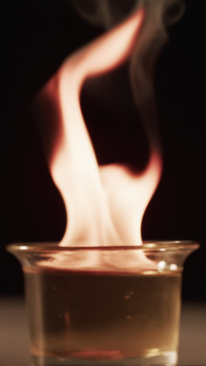 Vertical video of lit alcohol flames and copy space on black background