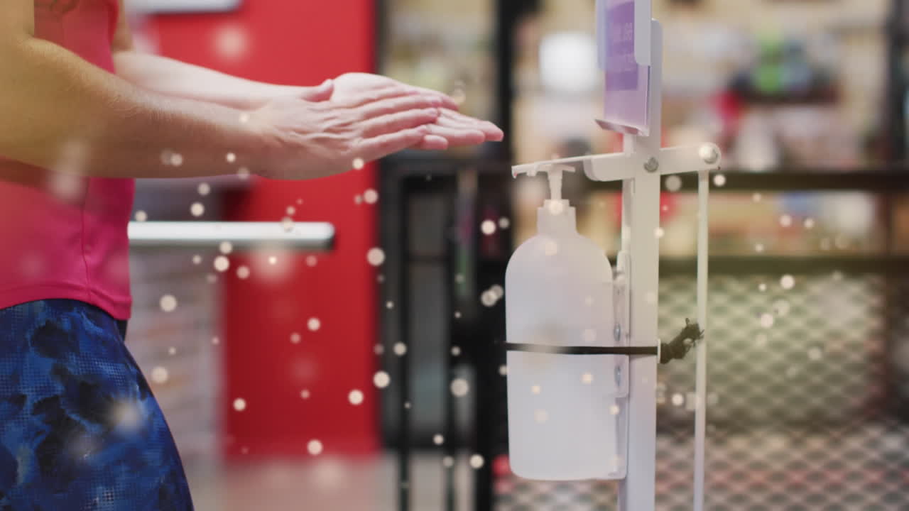 Animation of light spots over african american woman disinfecting hands, slow motion