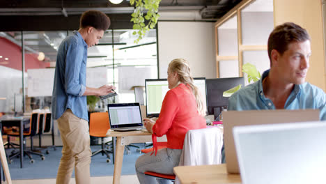happy diverse male and female colleague in discussion at desk in casual office, slow motion