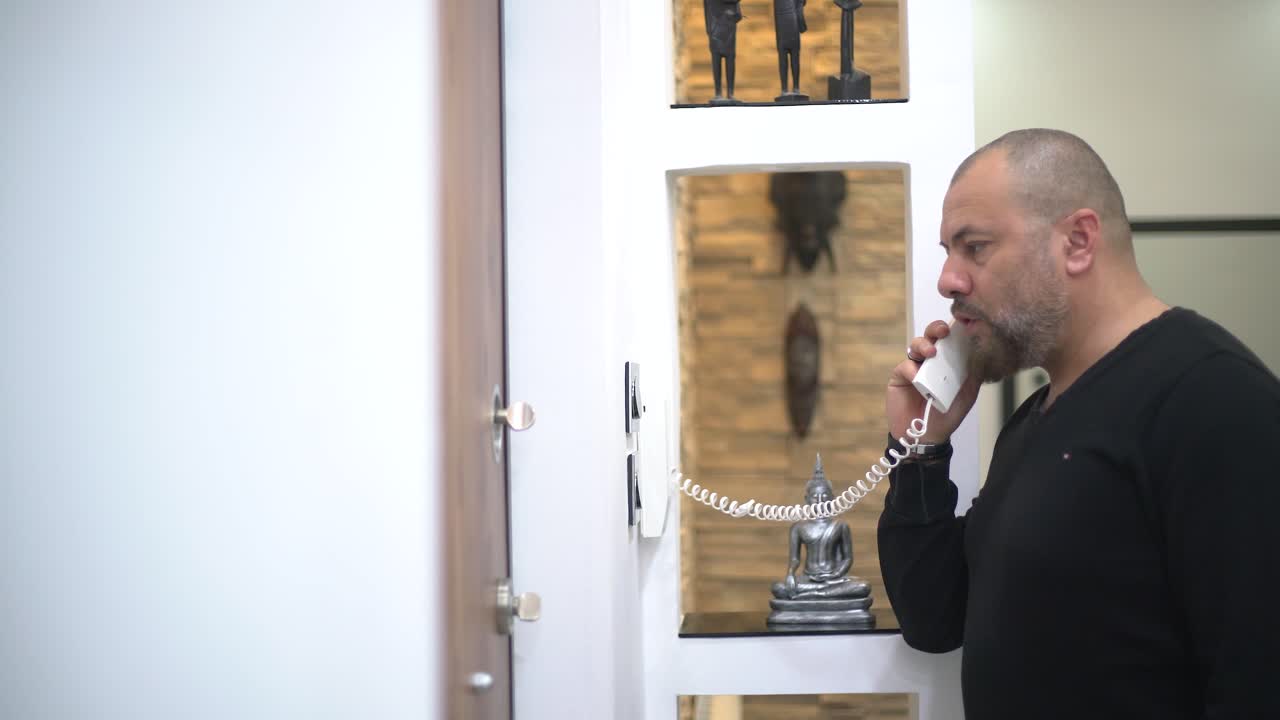 un hombre habla en el intercomunicador y presiona el botón para abrir la puerta