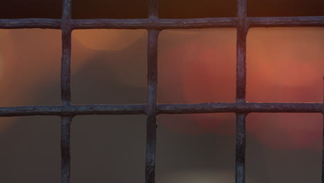 Closeup-rough-squared-iron-netting.-Blurred-orange-red-Bokeh-lights-flowing.