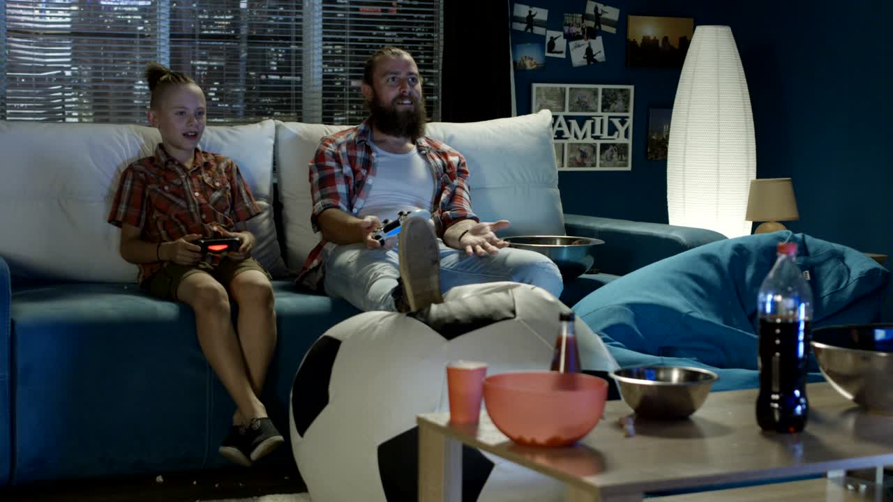 재미있는 아버지와 아들이 재미있고 비디오 게임을 하고 있습니다.