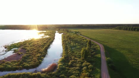 sun reflection on lake water in latvia landscape, aerial fly forward view