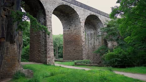 Große-Gewölbte-Brücke,-Die-Tief-Unten-Mit-Sich-Bewegenden-Bäumen-Erschossen-Wurde