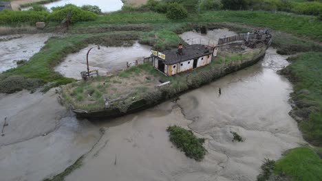 wooden lighterboat stranded and stuck in the marsh at wat tyler country park, cloudy basildon, uk - aerial view