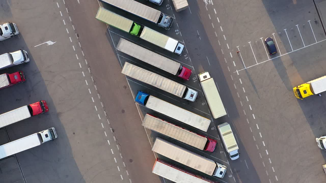 많은 트럭이 상품을 하역하고 있는 산업 창고 보관 건물 적재 구역을 떠나는 세미 트레일러가 부착된 트럭의 항공 샷