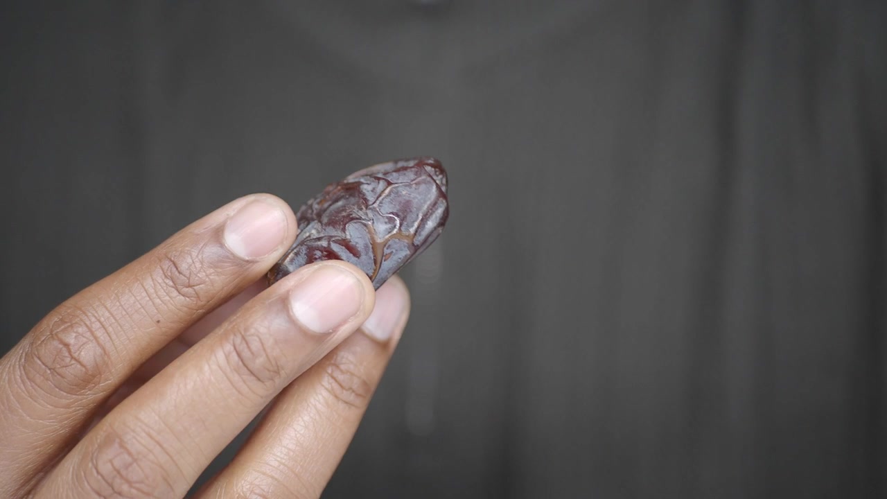 Primer plano de una mano sosteniendo un solo dátil