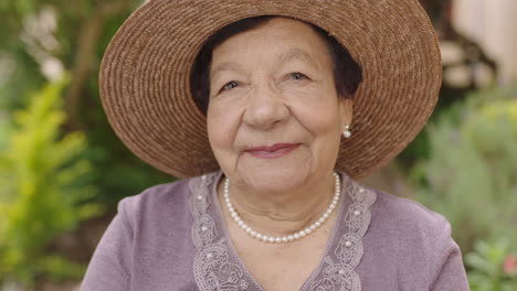 close up portrait of beautiful elderly woman looking smiling at camera wearing hat in garden enjoying peaceful day