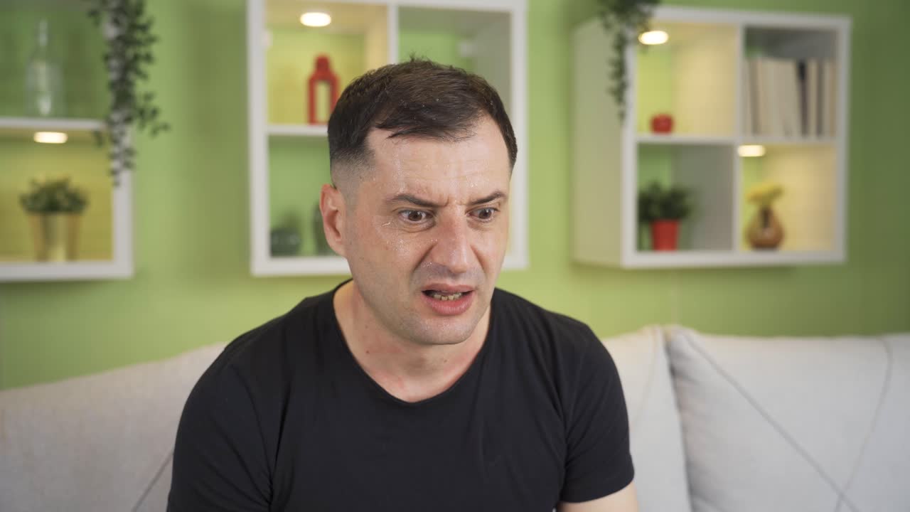 el hombre enfermo en casa está sudando, deprimido, estresado, y tiene fiebre alta.