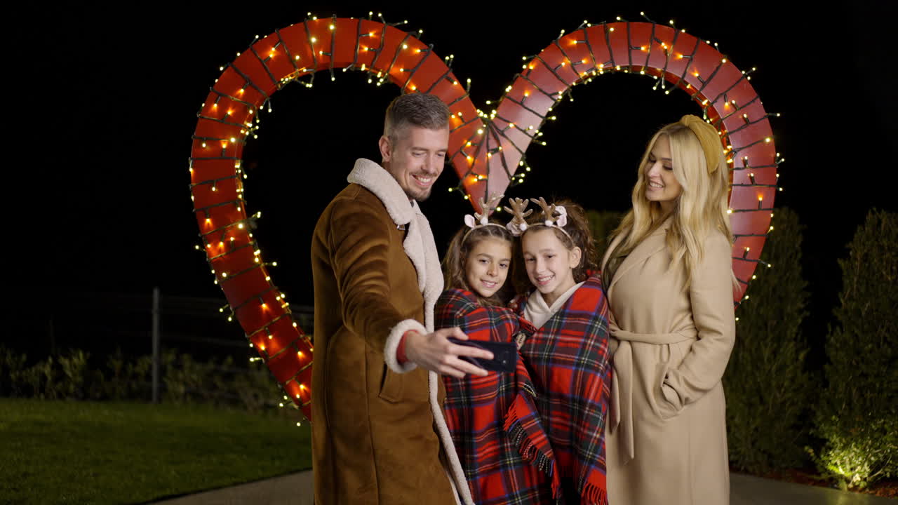 Family portrait in front of a heart decoration at night
