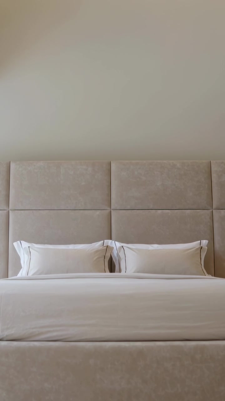 Vertical video: Moving up camera revealing bed centered in room, showing headboard and cove lights